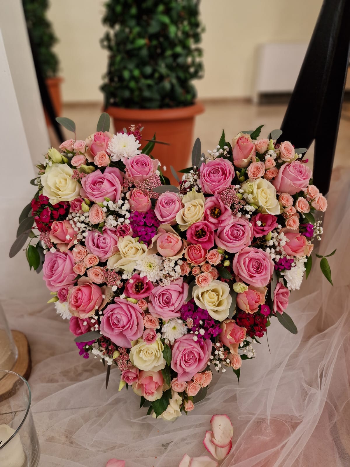 Herzförmiges Gesteck aus rosafarbenen und cremeweißen Rosen mit Schleierkraut