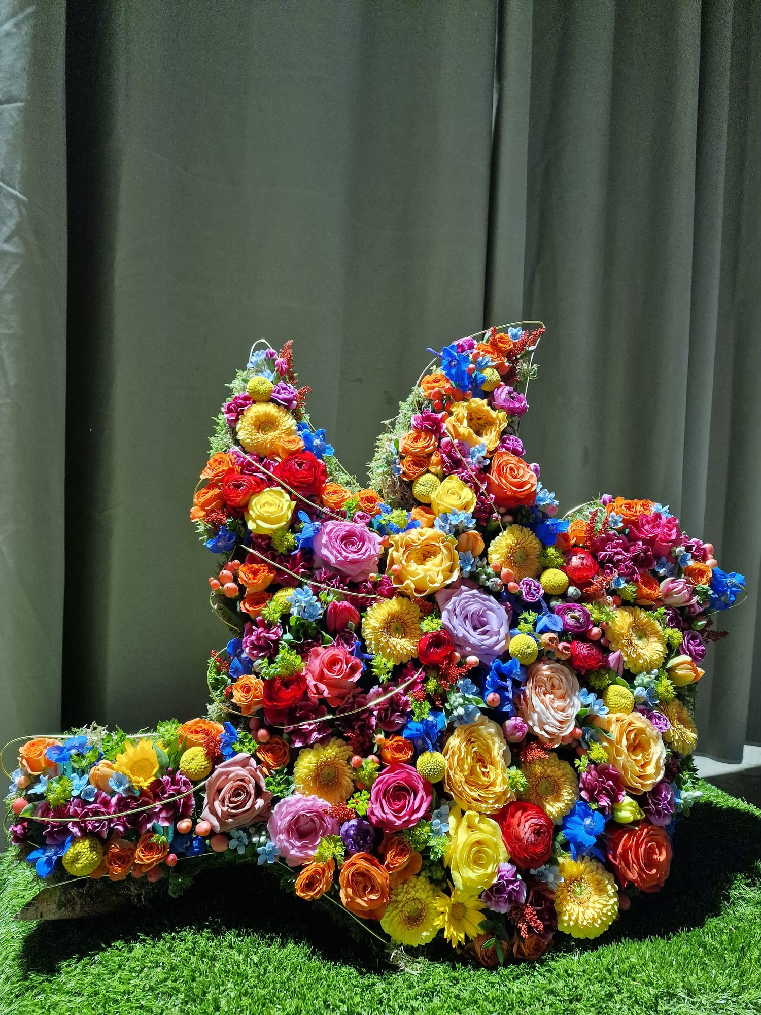 Großes Gesteck in Vogelform aus Rosen, Gerbera und Rittersporn in kräftigen Farben