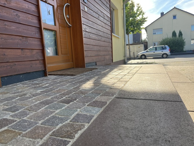 Neu gepflasterter Hauseingang mit Natursteinpflaster und angrenzender Plattenfläche